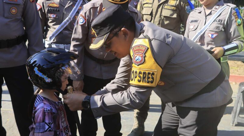 Kapolres Probolinggo, AKBP Wisnu Wardana memberi helm anak kecil saat Operasi Patuh Semeru 2024. (Foto: Humas Polres).